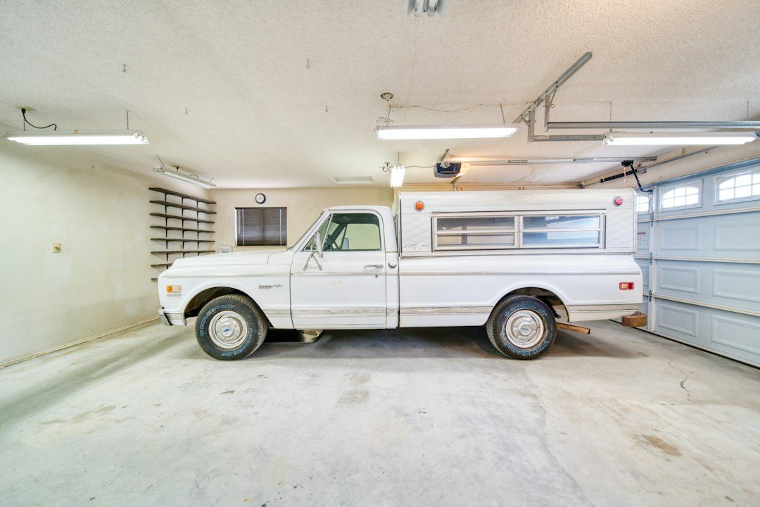 A white truck parked in a garage next to a garage door